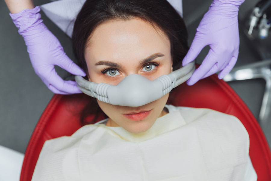 Paciente utilizando máscara de sedação consciente com óxido nitroso e oxigênio durante procedimento odontológico para maior conforto e relaxamento.