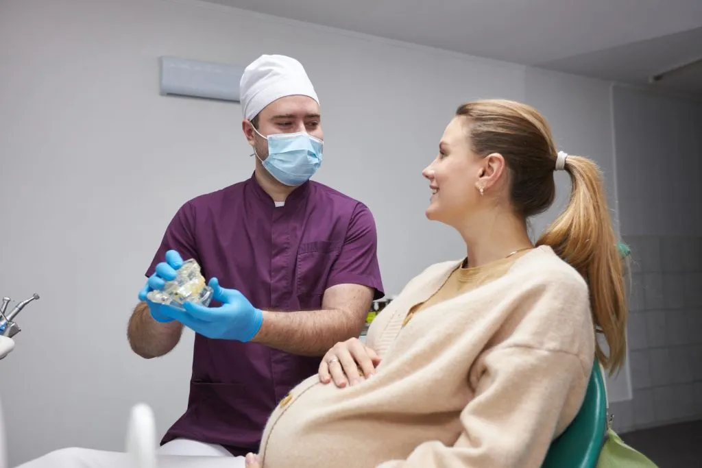 Grávida em clínica odontológica, sendo avaliada pelo cirurgião dentista.
